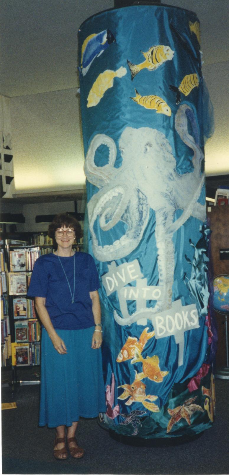 Photograph of Jo Osborne with "Dive into Books" Pillar