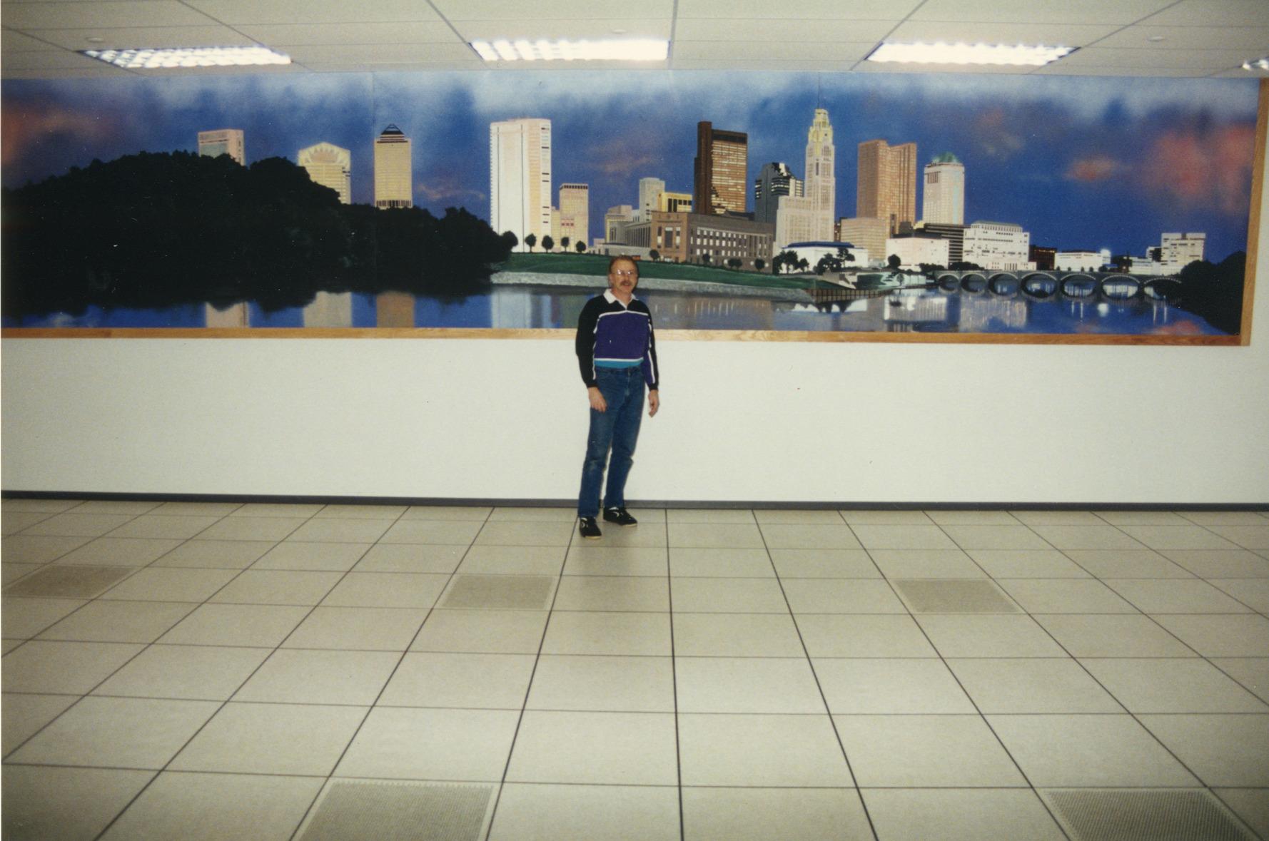 Photograph of William (bc) (Bill) Collins in Front of his Painting of the Columbus Skyline