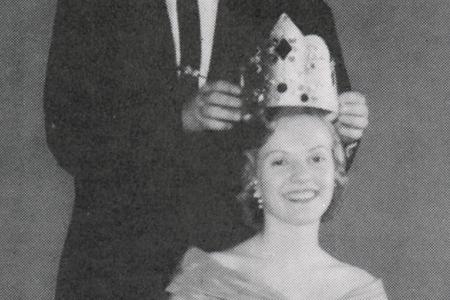 Black and white image of a student being crowned queen by another student from 1958 Cardinal yearbook
