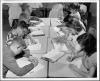 Black and white photo of children at desk cluster with heads bent over open books